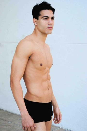 Ray Diaz modeling polaroid, side stance against a white wall